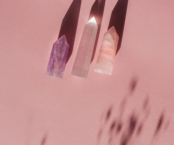 A person meditating peacefully surrounded by abstract pink light patterns.