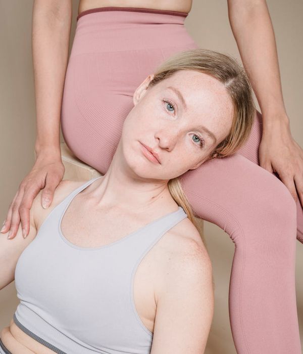 Woman in a calm yoga pose in a studio with soft cream colors.